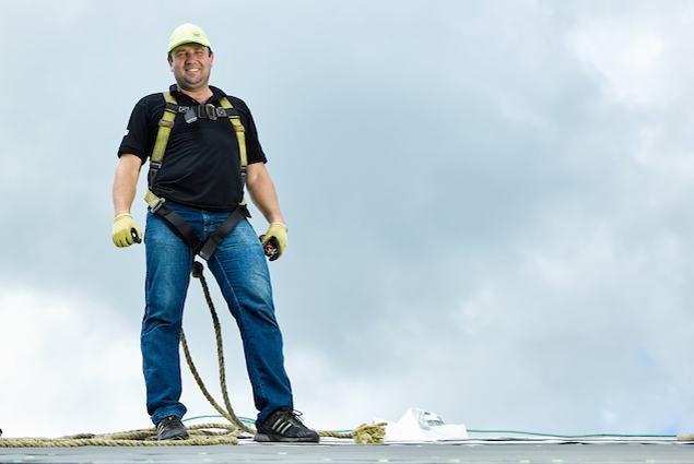 Man standing on roof wearing rope gear