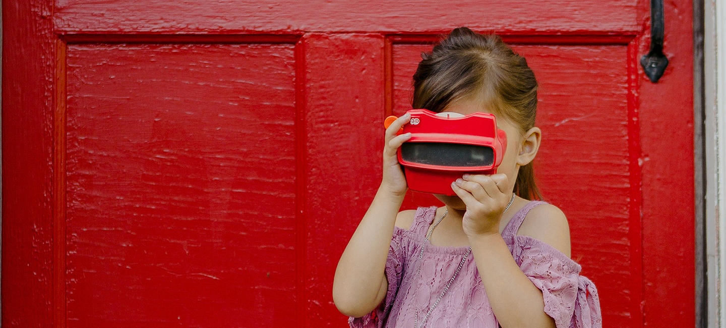 Girl with silver necklace holding a red ViewMaster