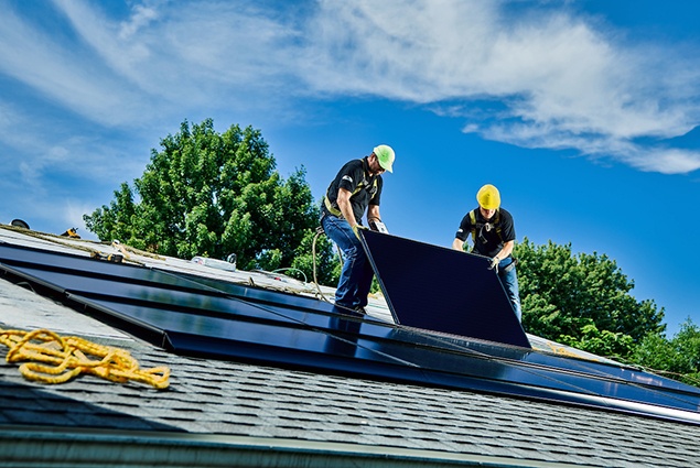 Two men installing GAF Energy solar panels and shingles