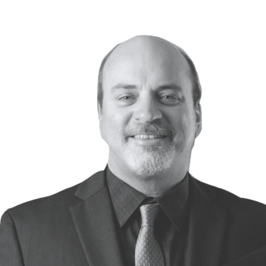 Black and white headshot of man in a beard wearing a suit