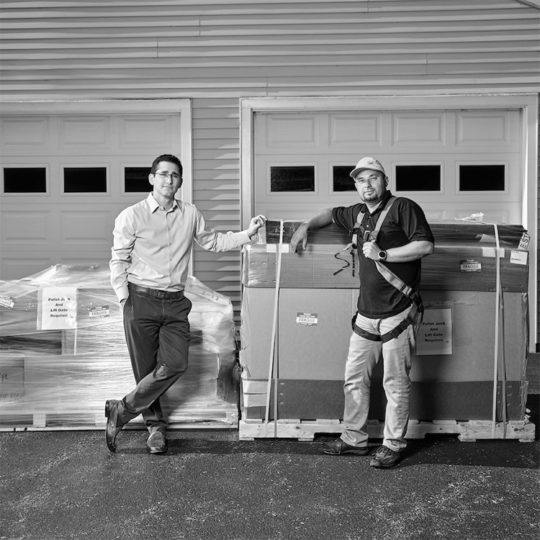 Black and white image of solar energy workers in front of a garage with pallets